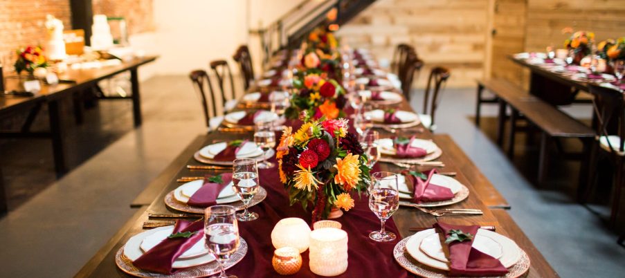 A long table with luxury plates and decorated with colorful flowers and candles