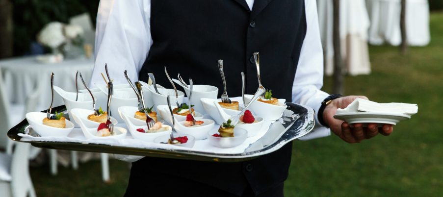 Waiter carries plate with tasty snacks